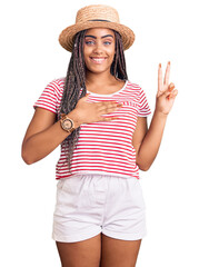 Young african american woman with braids wearing summer hat smiling swearing with hand on chest and...