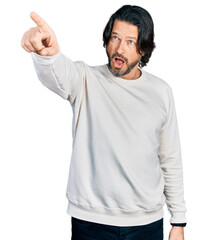 Middle age caucasian man wearing casual clothes pointing with finger surprised ahead, open mouth...