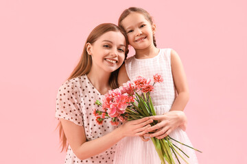 Cute little girl and her mother with flowers hugging on pink background
