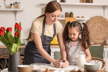 Little girl with her mom making dough in kitchen on Mother's Day