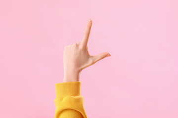 Young woman showing loser gesture on pink background