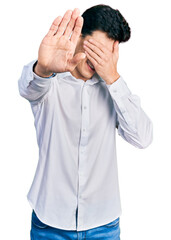 Young hispanic business man wearing business clothes covering eyes with hands and doing stop gesture with sad and fear expression. embarrassed and negative concept.