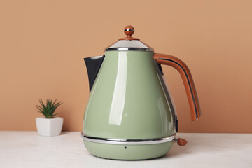 Electric kettle on table near brown wall, closeup