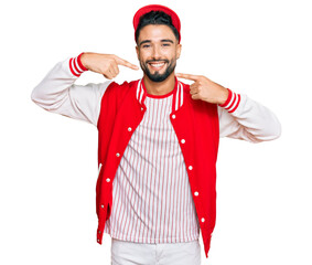 Young man with beard wearing baseball uniform smiling cheerful showing and pointing with fingers teeth and mouth. dental health concept.