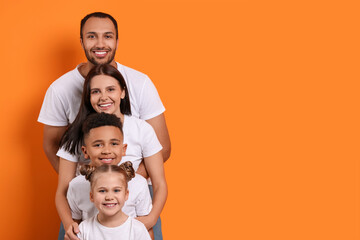 Happy international family with children on orange background. Space for text