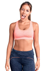 Young beautiful hispanic woman wearing sportswear winking looking at the camera with sexy...