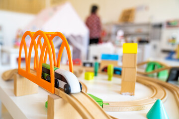 Green white wooden train toy crossing the bridge on river. Close up of wooden toy railway with...