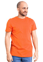 Fototapeta premium Young handsome man wering casual t shirt looking away to side with smile on face, natural expression. laughing confident.