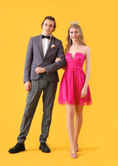 Beautiful couple dressed for prom on yellow background - obrazy, fototapety, plakaty