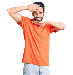 Young handsome man with beard wearing casual t-shirt smiling cheerful playing peek a boo with hands showing face. surprised and exited