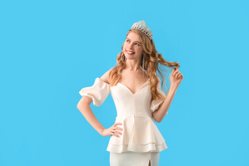 Teenage girl in tiara and prom dress on blue background © Pixel-Shot
