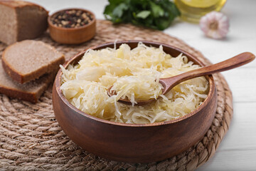Bowl of tasty sauerkraut on white wooden table, closeup