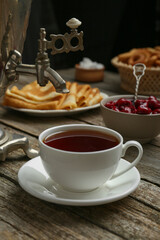 Metal samovar with cup of tea and treats on wooden table