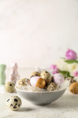 Obraz na płótnie Canvas Bowl with Easter quail eggs on white table