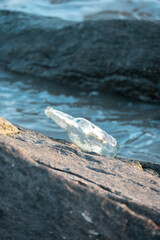 Botella apoyada sobre roca con mar de fondo