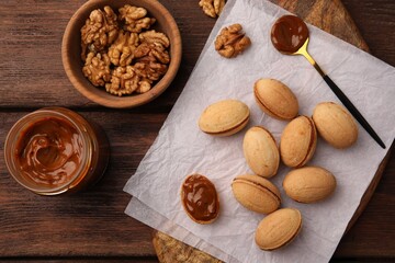Delicious nut shaped cookies with boiled condensed milk on wooden table, top view