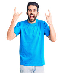 Young handsome man with beard wearing casual t-shirt shouting with crazy expression doing rock symbol with hands up. music star. heavy music concept.