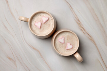 Cups of aromatic coffee with heart shaped marshmallows on white marble table, flat lay