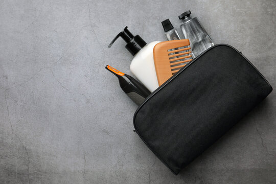 Preparation for spa. Compact toiletry bag with different cosmetic products on grey textured background, flat lay. Space for text