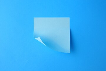 Blank paper note on light blue background, top view