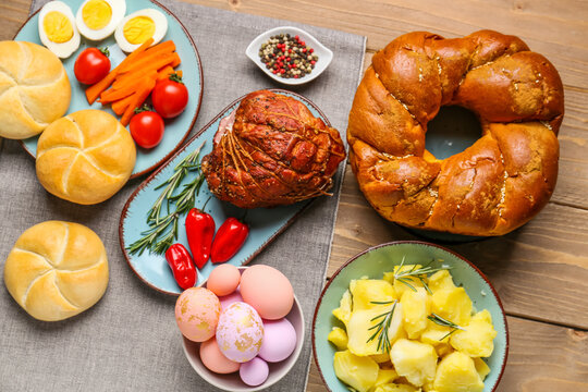 Tasty dishes and painted eggs for Easter dinner on wooden table
