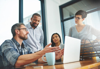 Working together to get the task done. Shot of businesspeople working together in the office.