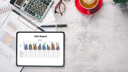 Tablet screen display with charts and reports on office desk workplace. Top view flat lay with copy...