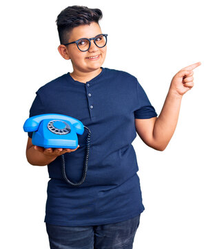 Little boy kid using vintage telephone smiling happy pointing with hand and finger to the side