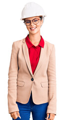 Young beautiful woman wearing architect hardhat looking positive and happy standing and smiling with a confident smile showing teeth