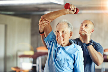 Not letting age affect his agility. Shot of a senior man working out with the help of a trainer.