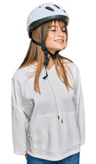 Teenager caucasian girl wearing bike helmet looking away to side with smile on face, natural expression. laughing confident.