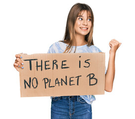 Teenager caucasian girl holding there is no planet b banner pointing thumb up to the side smiling happy with open mouth