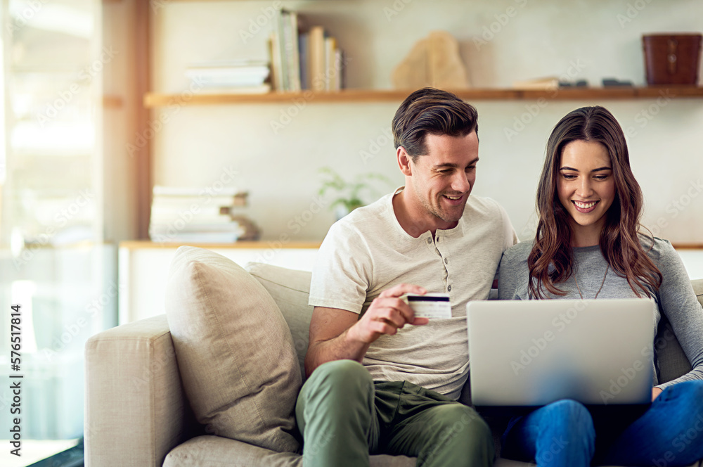 Wall mural Lets treat ourselves. Weve earned it. Shot of a happy young couple making a credit card payment on a laptop together at home.