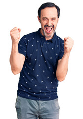 Middle age handsome man wearing casual polo screaming proud, celebrating victory and success very excited with raised arms