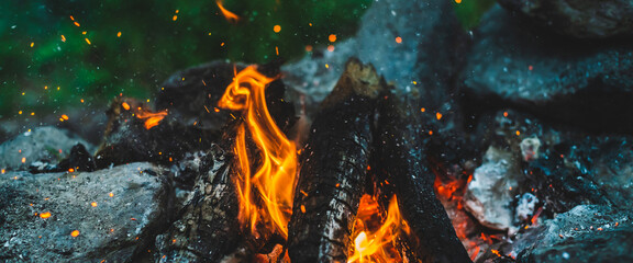 Vivid smoldered firewoods burned in fire closeup. Atmospheric background with orange flame of...