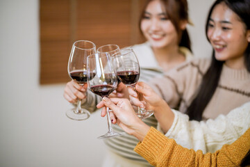 Cheerful friends enjoying home Birthday holiday party. Asian Friends cheering drinking red wine celebrating Christmas or New Year party