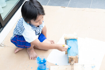 Asian kindergarten boy painting on a DIY craft project.
