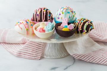 Decorated easter hot cocoa bombs on a pedestal stand, against a light background