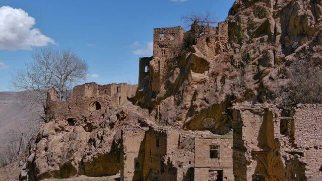 Close up drone shot of a ghost town in a desert. View on ruins of an ancient village on a mountain top.