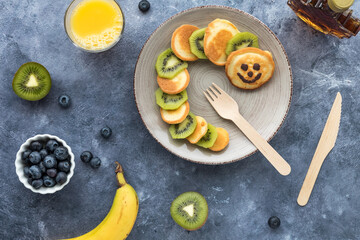 Homemade keto diet pancakes in the shape of a caterpillar with fruit and juice.