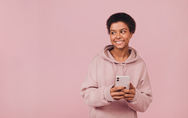 Happy attractive black girl using smartphone. Portrait with copy space. Cheerful smiling young...