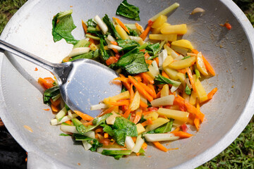 Beautiful, colourful and healthy Asian vegetable stir fry cooking in a wok in outdoors environment