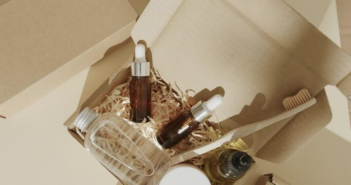 Close up of cardboard boxes with glass bottles, cream tub and toothbrush on beige background