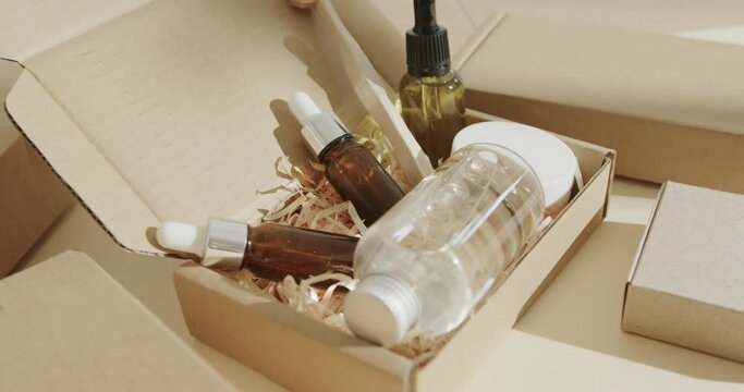 Close up of cardboard boxes with glass bottles, cream tub and toothbrush on beige background