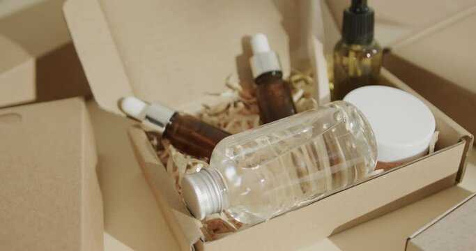 Close up of cardboard boxes with glass bottles, cream tub and toothbrush on beige background