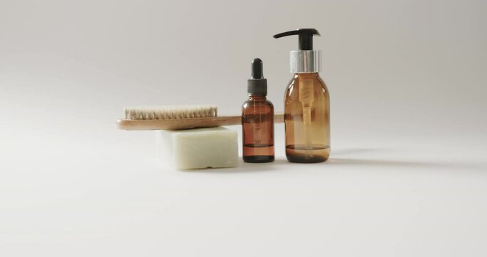Close up of glass bottles with pumps, soap, brush and copy space on white background