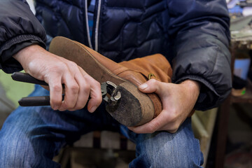 In workshop of master who specializes in shoe repairs shoes is being taken care