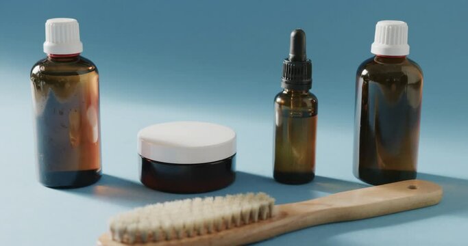 Close up of glass bottles, cream tub and brush with copy space on blue background