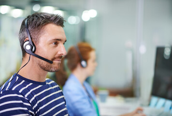 Providing professional customer support. Shot of a young businessman wearing a headset in an office...