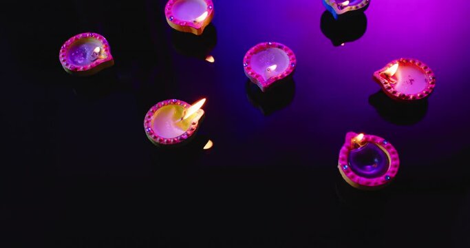 Close up of burning colourful candles celebrating diwali on black background